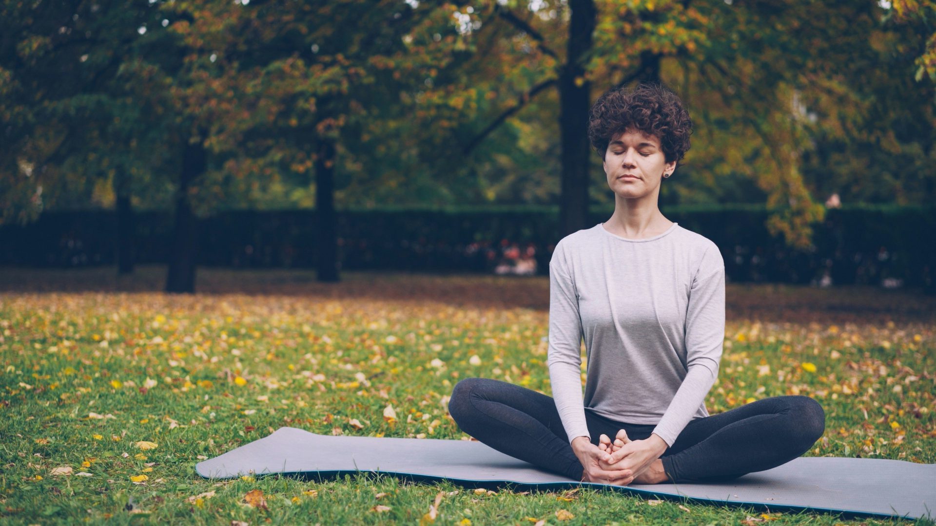 Woman meditating in a park on an autumn day