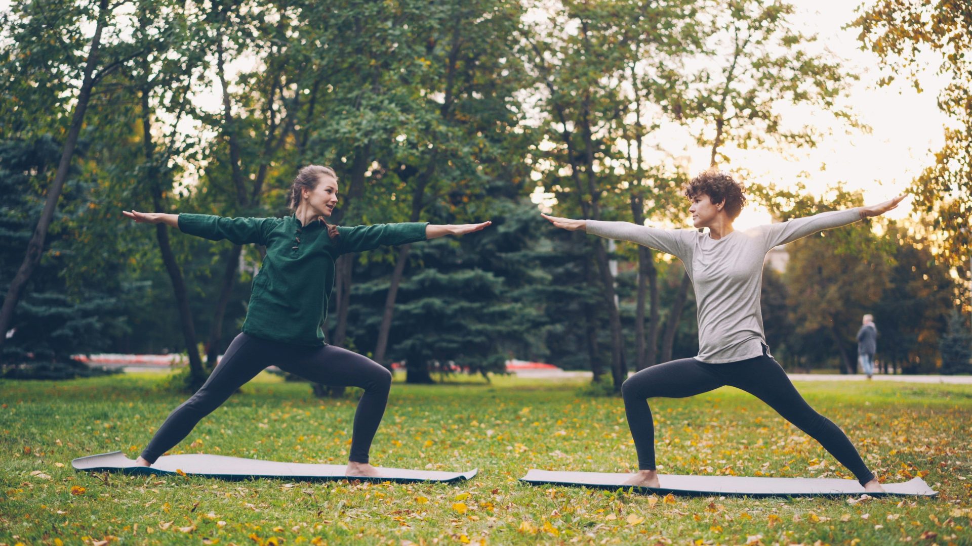 Two women practicing yoga in a park